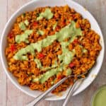 A bowl of shawarma rice with chickpeas and green tahini sauce.