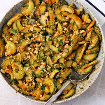 Cucumber salad with peanut dressing in a bowl with a spoon.