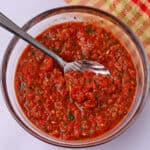 A bowl of red pepper harissa paste with a spoon.
