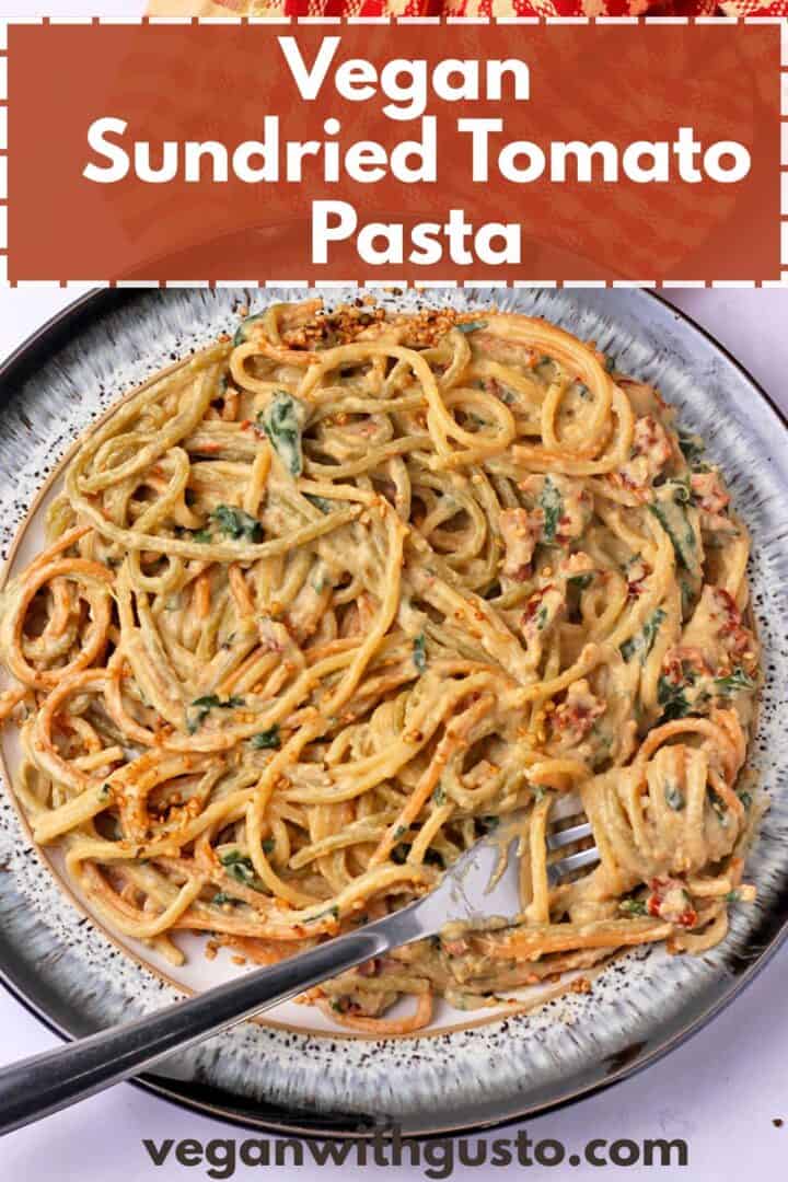 A plate of vegan sundried tomato pasta with a fork. Text overlay of recipe title on the photo.