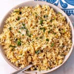 A bowl of coconut lime rice with chopped cilantro and chili flakes.