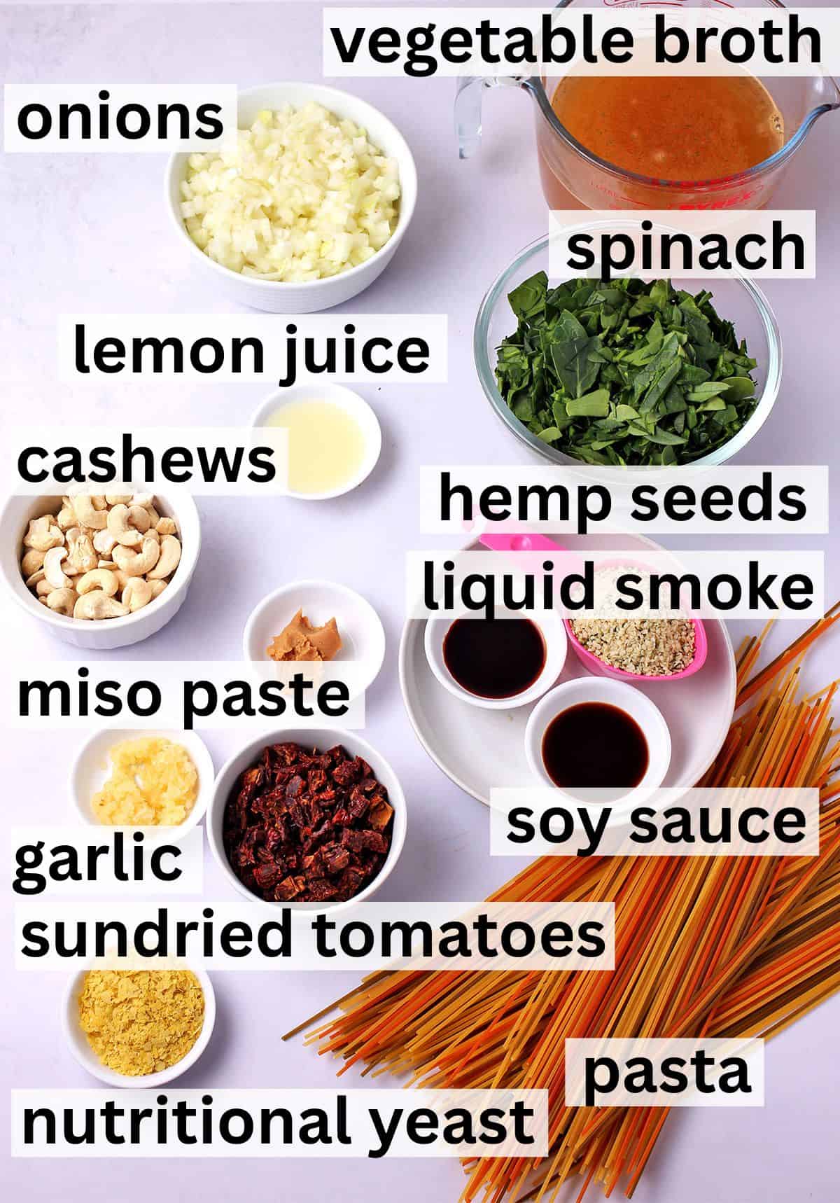 The ingredients for vegan sundried tomato pasta with spinach and bacon bits with labels.