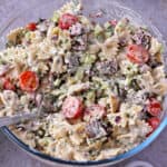 A bowl of vegan dill pickle pasta salad with bacon and tomatoes.