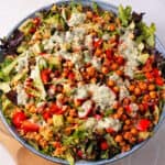 A bowl of bulgur salad with vegetables, chickpeas, and lemon tahini dressing.