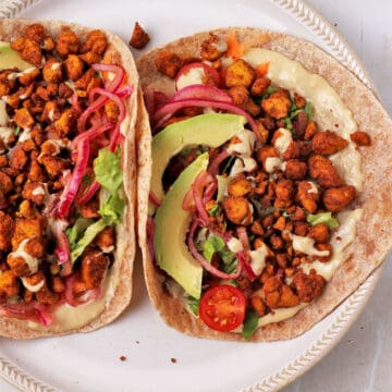 Tofu shawarma wraps with crumbled tofu shawarma, pickled onions, lettuce, tomatoes, avocado, and tahini dressing.