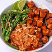 Lemongrass sauce with noodles, tofu, broccoli, and green beans in a bowl topped with chopped peanuts.
