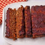 Baked vegan lentil loaf is sliced and placed on a white plate.