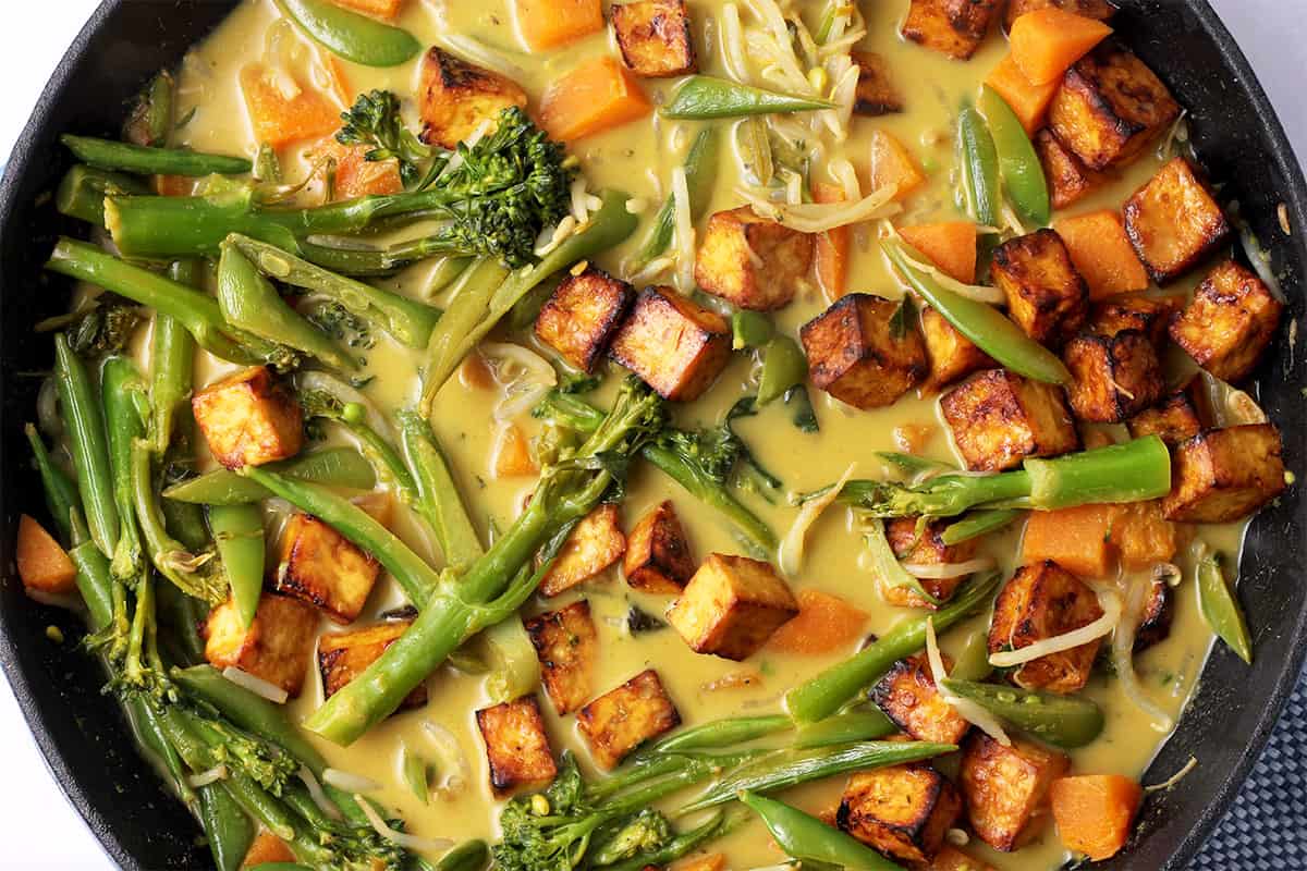 A pot of Thai green curry with vegetables, sweet potatoes, and tofu.
