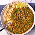 A bowl of spinach and lentil curry over noodles.