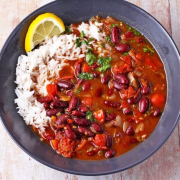 Kidney bean curry and white rice in a black bowl.