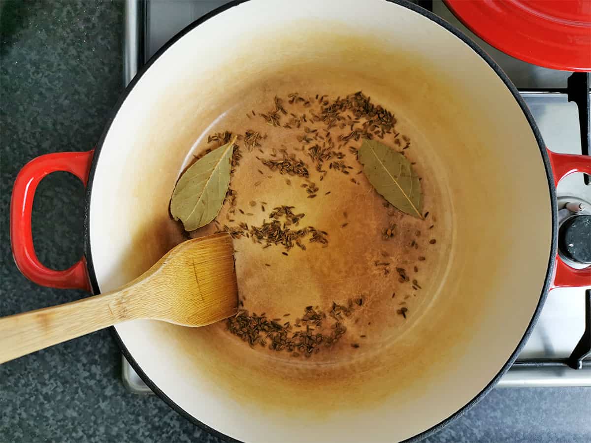 Cumin seeds, fenugreek seeds, and bay leaves are toasted in a Dutch oven.