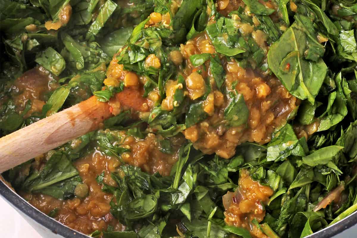 Chopped spinach is stirred into cooked red lentils.