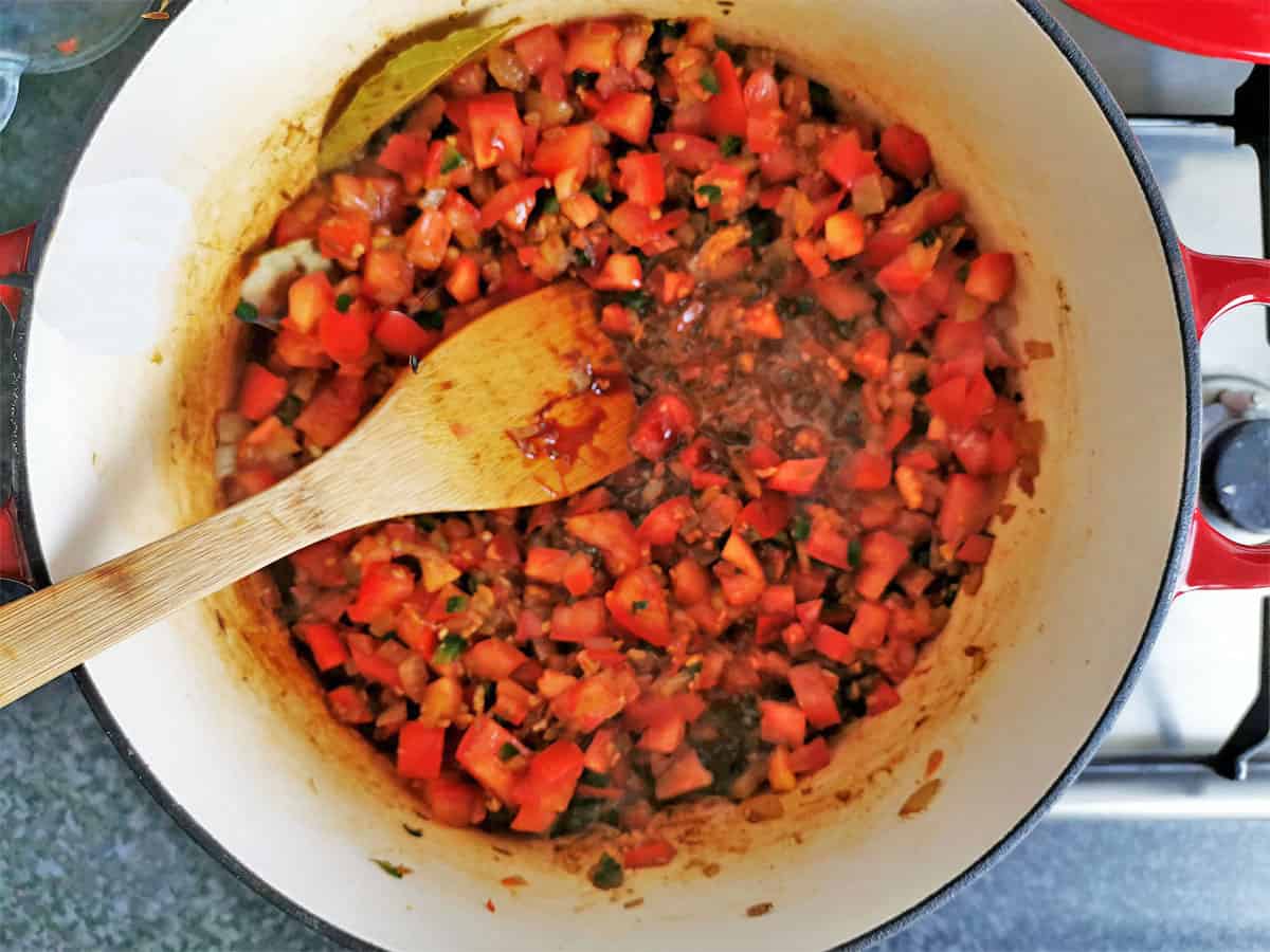 Diced tomatoes are stirred in a pot.