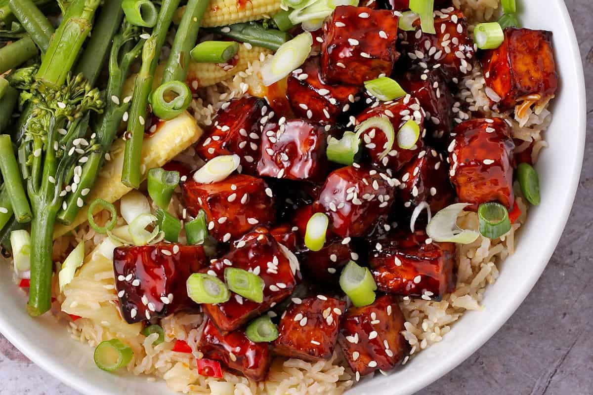 Tofu with teriyaki sauce in a bowl with rice and vegetables.