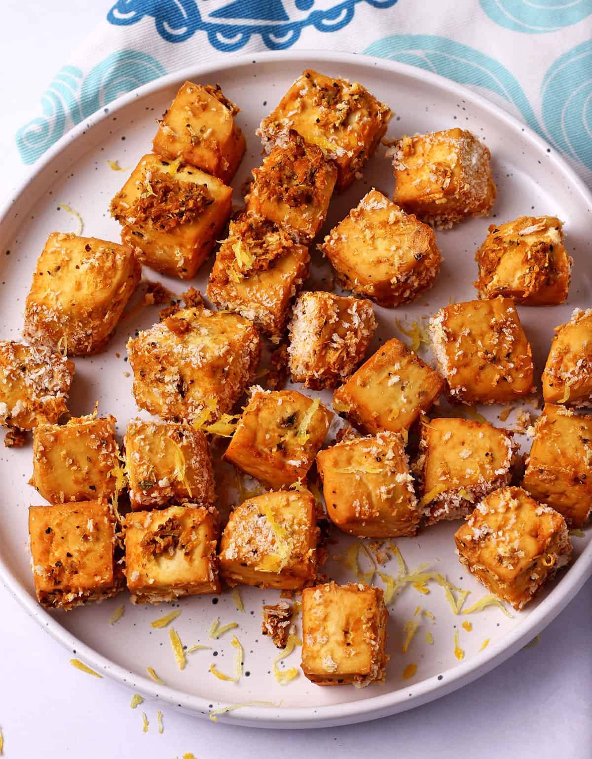 Lemon pepper panko tofu cubes in a plate with lemon zest.